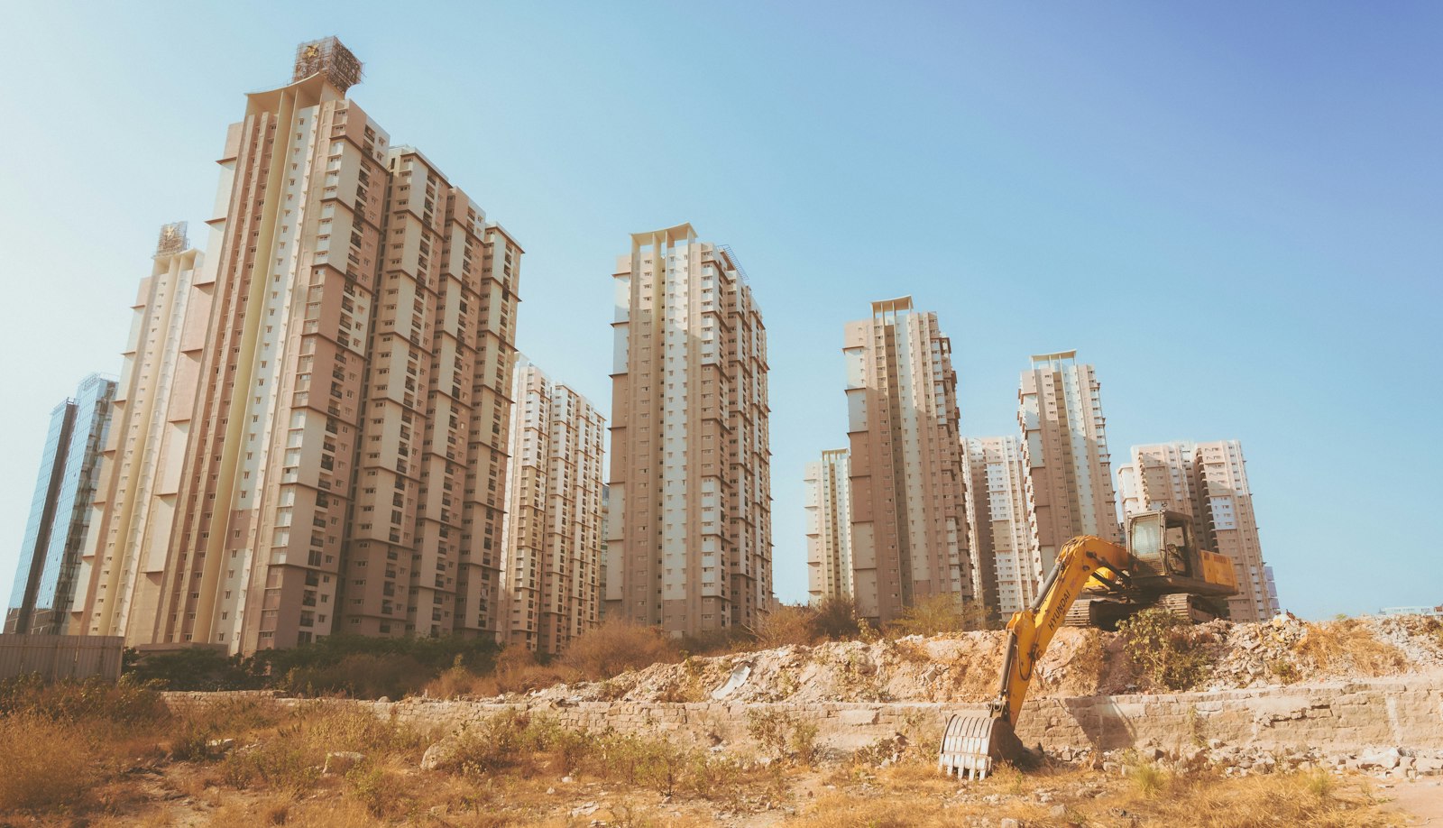 Escavatore al lavoro in un cantiere residenziale con edifici sullo sfondo