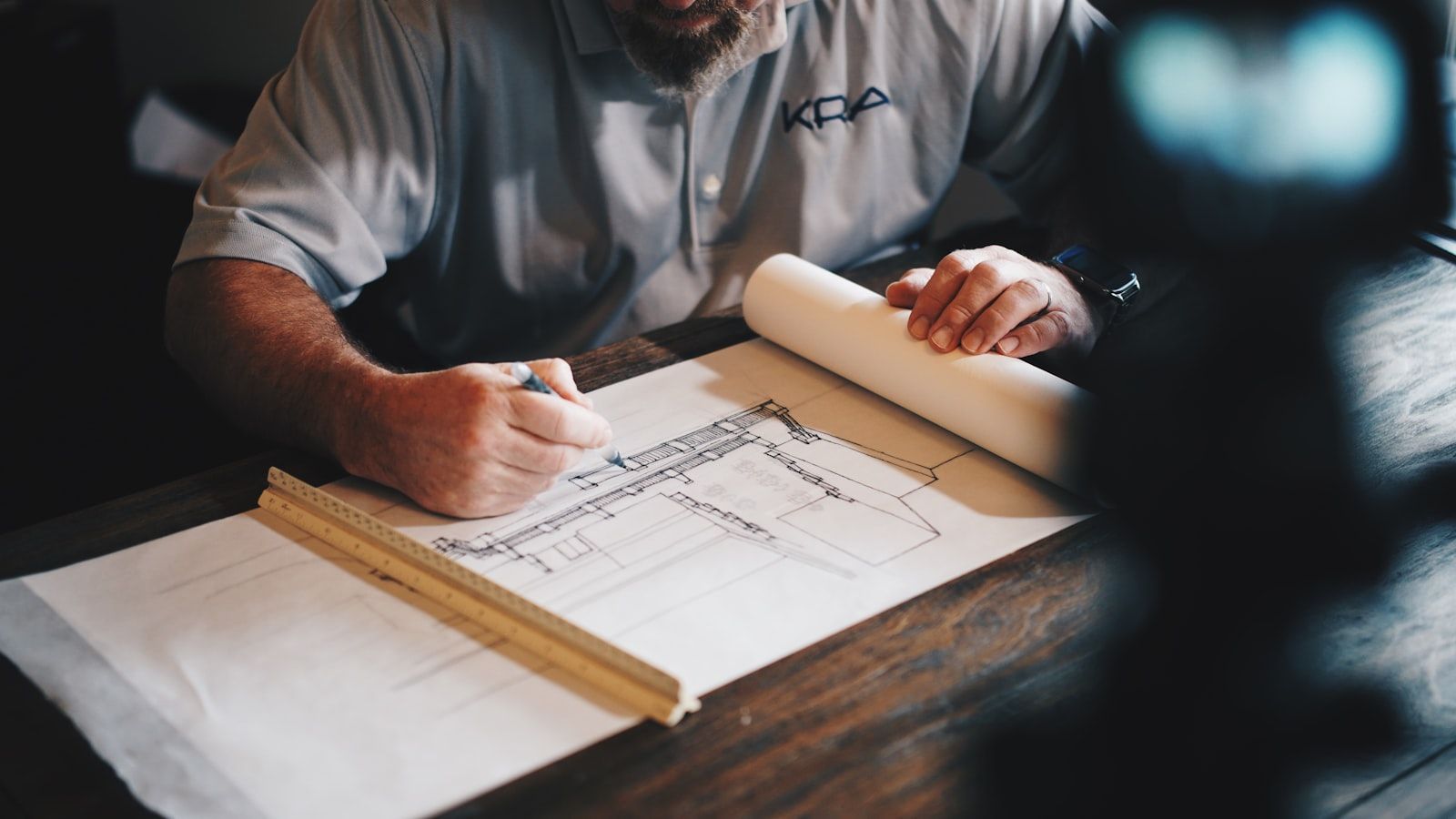 Architetto al lavoro su un disegno tecnico con matita e righello