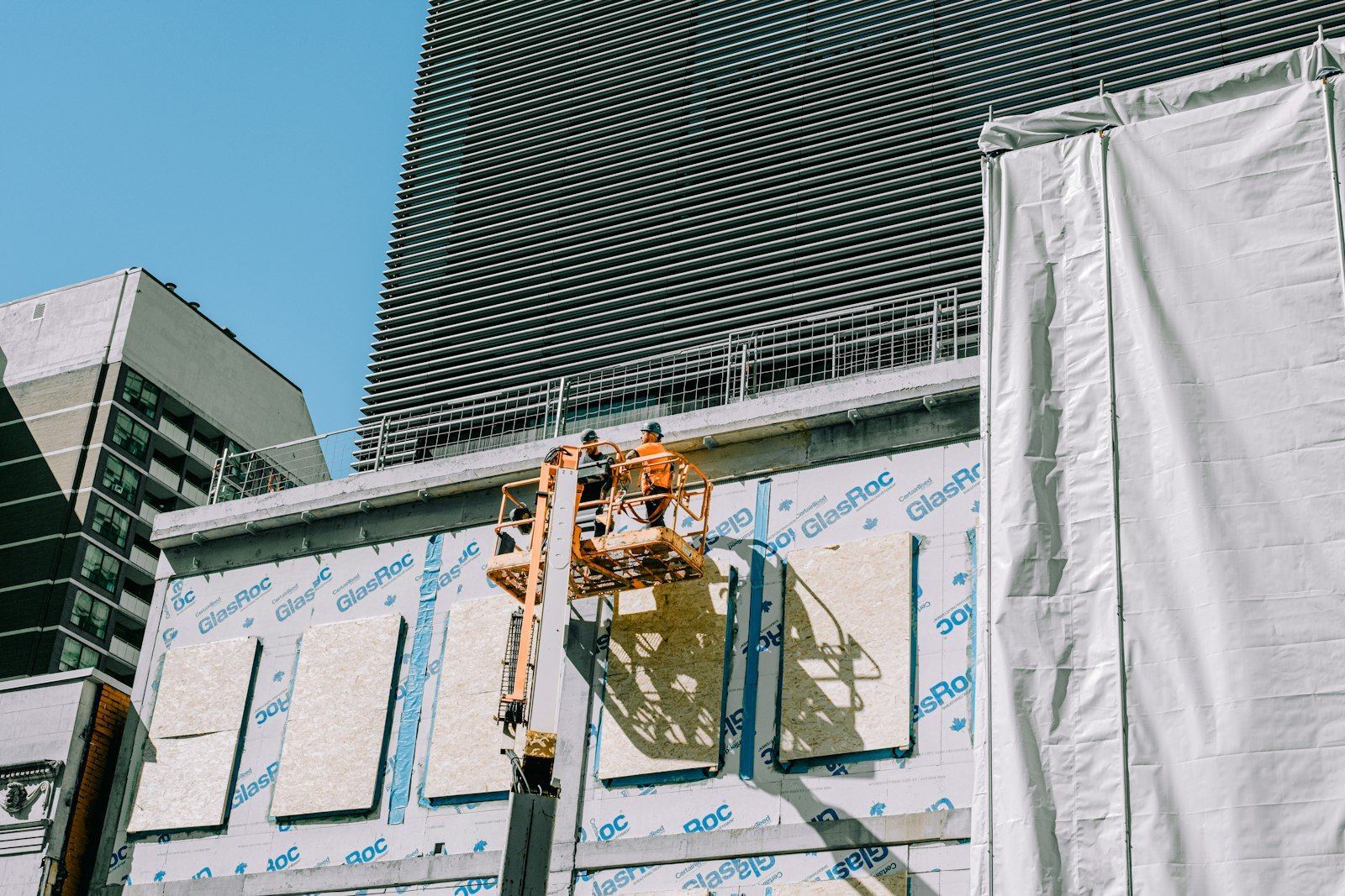 Operaio su piattaforma elevatrice che lavora sulla facciata di un edificio