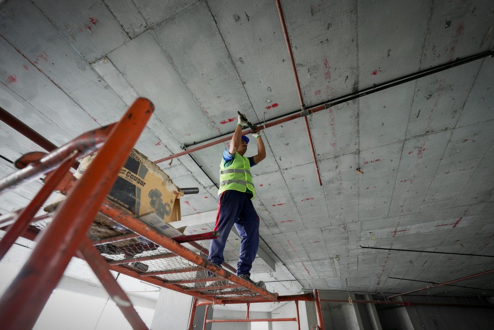 Operaio su scala che lavora alla posa di un controsoffitto