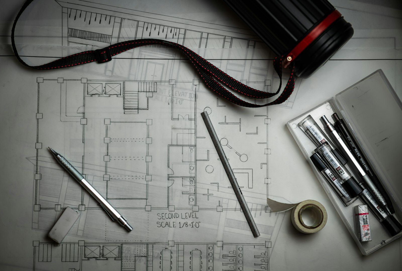 Planimetrie architettoniche arrotolate con squadra e righello su un tavolo da lavoro