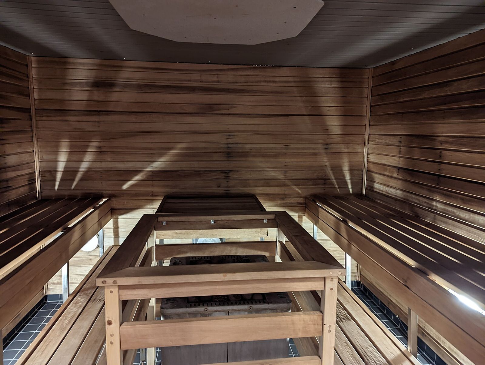 Interno di una sauna in legno con panche e stufa accesa