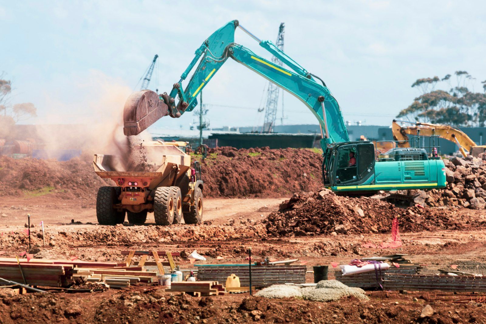 Escavatore che carica terra di scavo su un camion in cantiere